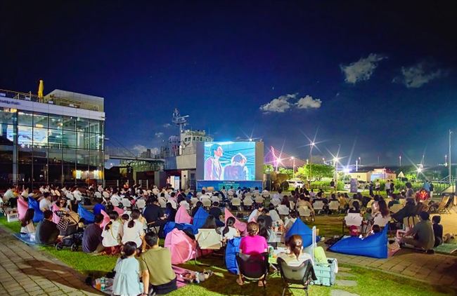 漢江フェスティバル夏の夜、漢江公園の芝生で野外シネマを楽しむ人々の写真